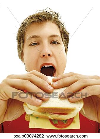 Young man biting a sandwich View Large Photo Image Stock Image - Young man biting a sandwich. Fotosearch