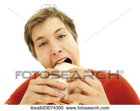 Young man biting a sandwich View Large Photo Image Stock Image - Young man biting a sandwich. Fotosearch