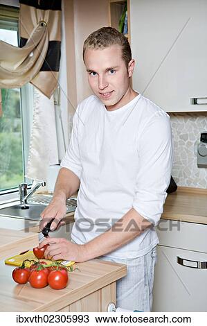 Young man cutting tomatoes in the kitchen View Large Photo Image Stock Image - Young man cutting tomatoes in the kitchen. Fotosearch