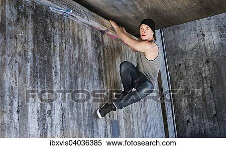"Young man hanging in a parkour move on concrete wall, Sweden, Europe" View Large Photo Image Stock Photography - "Young man hanging in a parkour move on concrete wall, Sweden, Europe". Fotosearch