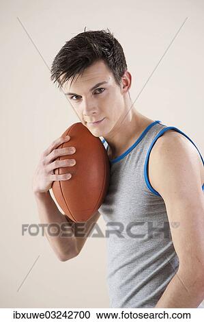 Stock Image - "Young man holding a football in his hand, Mannheim, Baden-Wurttemberg, Germany, Europe". Fotosearch
