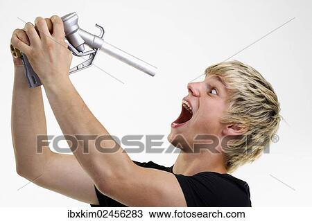 Young man holding a petrol pump nozzle in front of his open mouth View Large Photo Image Stock Image - Young man holding a petrol pump nozzle in front of his open mouth. Fotosearch