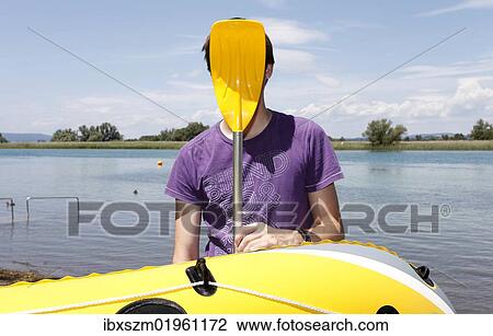 "Young man holding paddle of rubber dinghy in front of his face, having fun boating, transition of Lake Constance into Seerhein river and Untersee lake, Taegerwilen, Switzerland, Europe" View Large Photo Image Stock Image - "Young man holding paddle of rubber dinghy in front of his face, having fun boating, transition of Lake Constance into Seerhein river and Untersee lake, Taegerwilen, Switzerland, Europe". Fotosearch