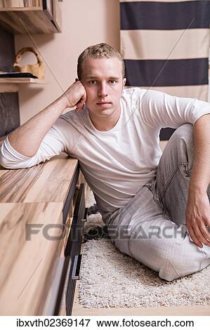Stock Photo - Young man in a living room. Fotosearch