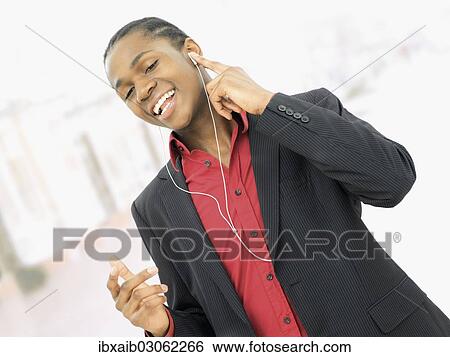 Young man listening to music View Large Photo Image Stock Photograph - Young man listening to music. Fotosearch