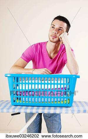 Stock Image - "Young man looking desperate while leaning on an ironing board, Mannheim, Baden-Wurttemberg, Germany, Europe". Fotosearch