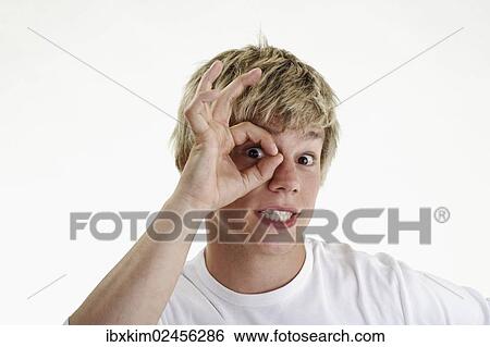Young man looking through a ring made of his pointer finger and thumb View Large Photo Image Stock Photograph - Young man looking through a ring made of his pointer finger and thumb. Fotosearch