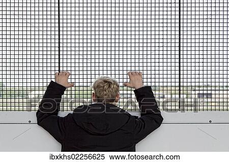 "Young man looking through a metal-grilled window onto the runway, Berlin, Germany, Europe" View Large Photo Image Stock Photography - "Young man looking through a metal-grilled window onto the runway, Berlin, Germany, Europe". Fotosearch