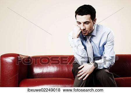 Young man sitting pensively on a sofa and waiting View Large Photo Image Stock Photo - Young man sitting pensively on a sofa and waiting. Fotosearch
