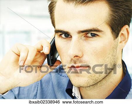 "Young man speaking on his mobile phone, serious face" View Large Photo Image Stock Photograph - "Young man speaking on his mobile phone, serious face". Fotosearch