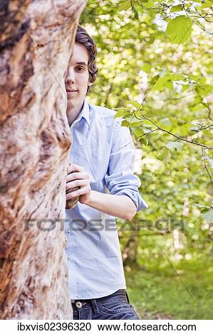 "Young man standing by a tree in the woods, Sweden, Europe" View Large Photo Image Stock Image - "Young man standing by a tree in the woods, Sweden, Europe". Fotosearch