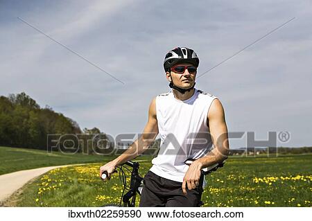 Stock Image - Young man taking a break at cycling. Fotosearch