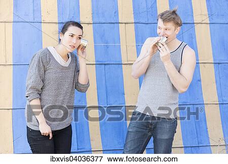 "Young man talking into a tin can phone and young woman listening, conceptual image of communication in a relationship" View Large Photo Image Stock Photo - "Young man talking into a tin can phone and young woman listening, conceptual image of communication in a relationship". Fotosearch