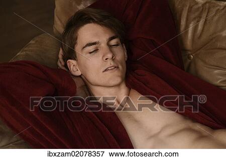 Young man wearing a red bath robe lying on a sofa View Large Photo Image Stock Photo - Young man wearing a red bath robe lying on a sofa. Fotosearch