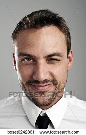 Stock Image - "Young man wearing a shirt and a tie, blinking an eye, portrait". Fotosearch