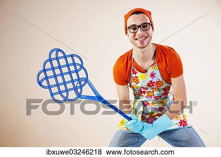 "Young man wearing an apron and holding a carpet beater, Mannheim, Baden-Wurttemberg, Germany, Europe" View Large Photo Image Stock Photo - "Young man wearing an apron and holding a carpet beater, Mannheim, Baden-Wurttemberg, Germany, Europe". Fotosearch