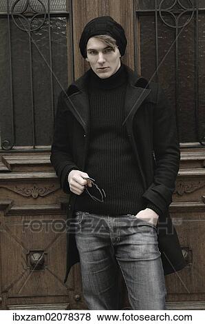 Stock Photo - "Young man wearing winter clothes, standing in front of a front door". Fotosearch
