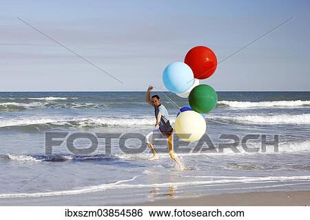 Young man with large colourful balloons at the beach View Large Photo Image Stock Photograph - Young man with large colourful balloons at the beach. Fotosearch