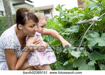 Stock Image - Young mother with her daughter in a garden. Fotosearch
