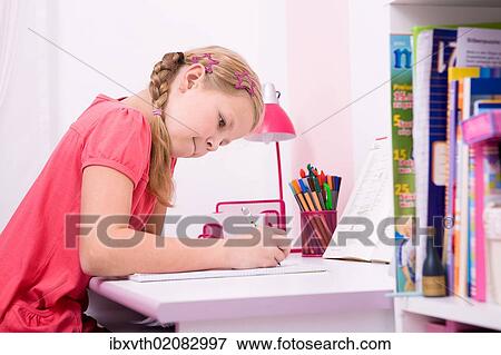 Young schoolgirl doing her homework at her desk View Large Photo Image Stock Photo - Young schoolgirl doing her homework at her desk. Fotosearch