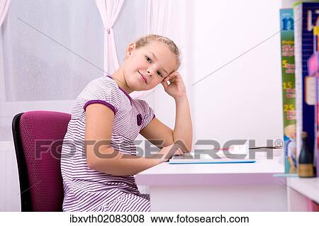 Young schoolgirl doing her homework at her desk View Large Photo Image Stock Photo - Young schoolgirl doing her homework at her desk. Fotosearch