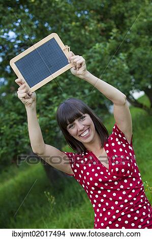"Young woman, 25, holding a blackboard in her hands" View Large Photo Image Picture - "Young woman, 25, holding a blackboard in her hands". Fotosearch