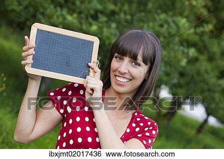 "Young woman, 25, holding a blackboard in her hands" View Large Photo Image Stock Photograph - "Young woman, 25, holding a blackboard in her hands". Fotosearch