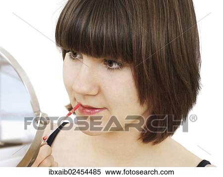 Young woman applying lip gloss View Large Photo Image Stock Photography - Young woman applying lip gloss. Fotosearch