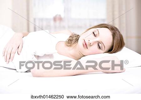 Stock Image - Young woman asleep in bed. Fotosearch