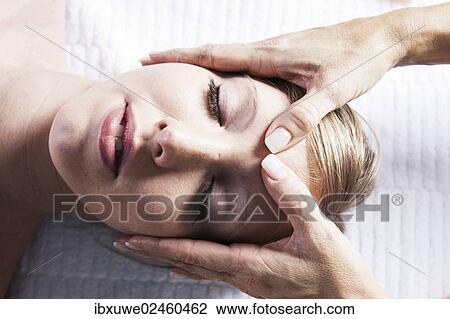 Stock Image - Young woman being treated by a therapist on her head and upper torso. Fotosearch
