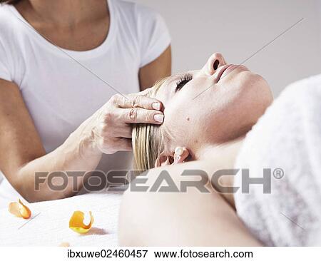 Stock Photo - Young woman being treated by a therapist on her head and upper torso. Fotosearch