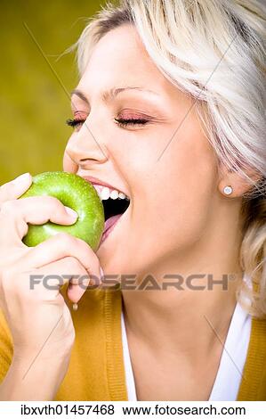 Stock Photo - Young woman biting into apple. Fotosearch