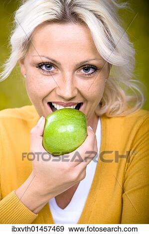 Young woman biting into apple View Large Photo Image Stock Photo - Young woman biting into apple. Fotosearch