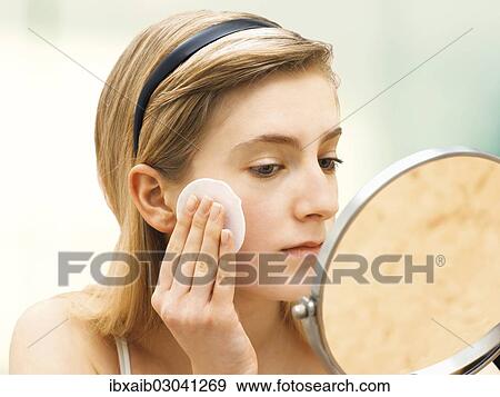 Stock Photo - Young woman cleaning her face with a cotton pad. Fotosearch