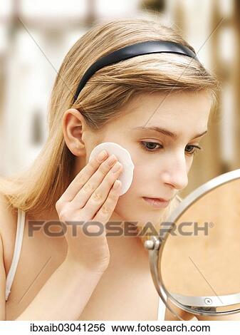 Stock Photograph - Young woman cleaning her face with a cotton pad. Fotosearch