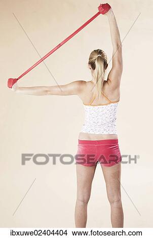 Picture - Young woman doing exercises with a Theraband. Fotosearch