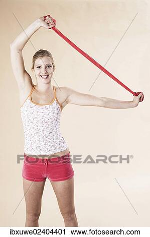 Stock Image - Young woman doing exercises with a Theraband. Fotosearch