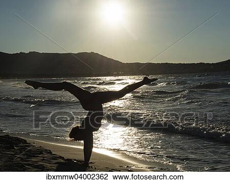 "Young woman doing gymnastics on the beach, backlight, Corsica, France, Europe" View Large Photo Image Stock Image - "Young woman doing gymnastics on the beach, backlight, Corsica, France, Europe". Fotosearch