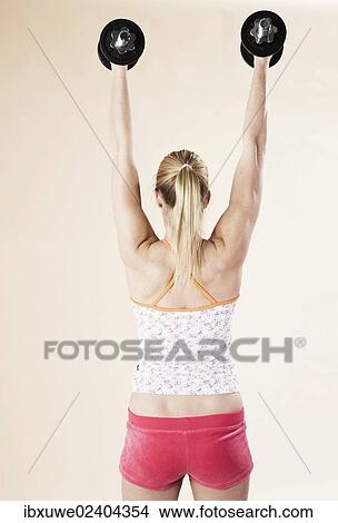 Young woman doing strength training with dumbbells View Large Photo Image Picture - Young woman doing strength training with dumbbells. Fotosearch