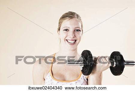 Young woman doing strength training with dumbbells View Large Photo Image Stock Image - Young woman doing strength training with dumbbells. Fotosearch