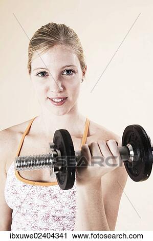 Stock Image - Young woman doing strength training with a dumbbell. Fotosearch