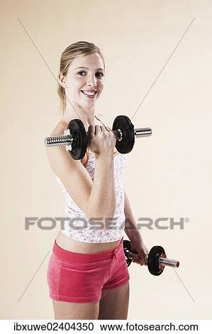 Young woman doing strength training with dumbbells View Large Photo Image Stock Image - Young woman doing strength training with dumbbells. Fotosearch