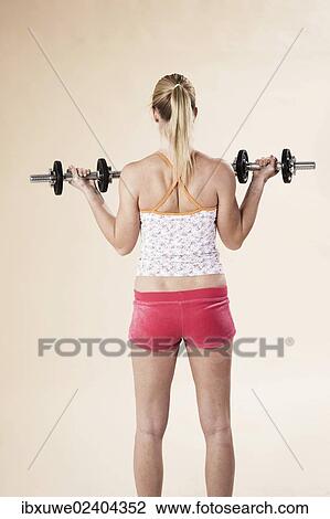 Stock Image - Young woman doing strength training with dumbbells. Fotosearch