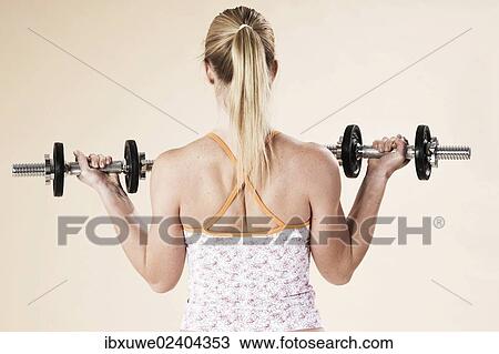 Young woman doing strength training with dumbbells View Large Photo Image Stock Image - Young woman doing strength training with dumbbells. Fotosearch