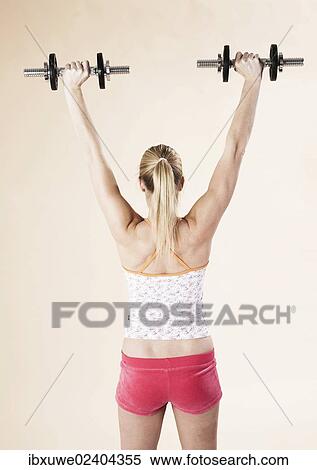 Stock Photography - Young woman doing strength training with dumbbells. Fotosearch