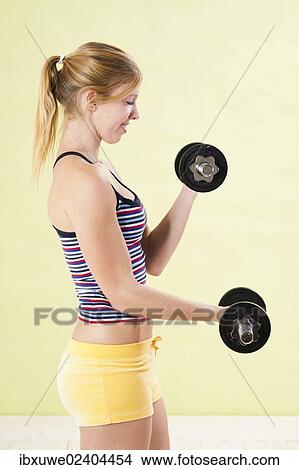 Young woman during strength training with dumbbells View Large Photo Image Picture - Young woman during strength training with dumbbells. Fotosearch