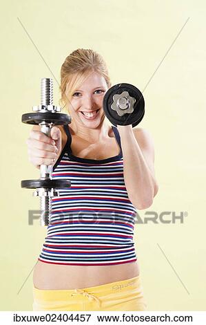 Stock Photo - Young woman during strength training with dumbbells. Fotosearch