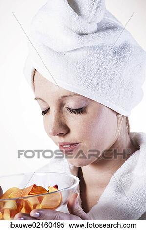 Stock Photography - Young woman enjoying the fragrance of rose petals. Fotosearch