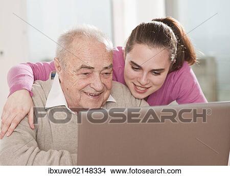 Young woman explaining the computer to an elderly man View Large Photo Image Picture - Young woman explaining the computer to an elderly man. Fotosearch