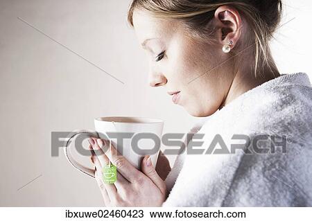 Young woman holding a cup of tea in her hand and relaxing View Large Photo Image Stock Image - Young woman holding a cup of tea in her hand and relaxing. Fotosearch